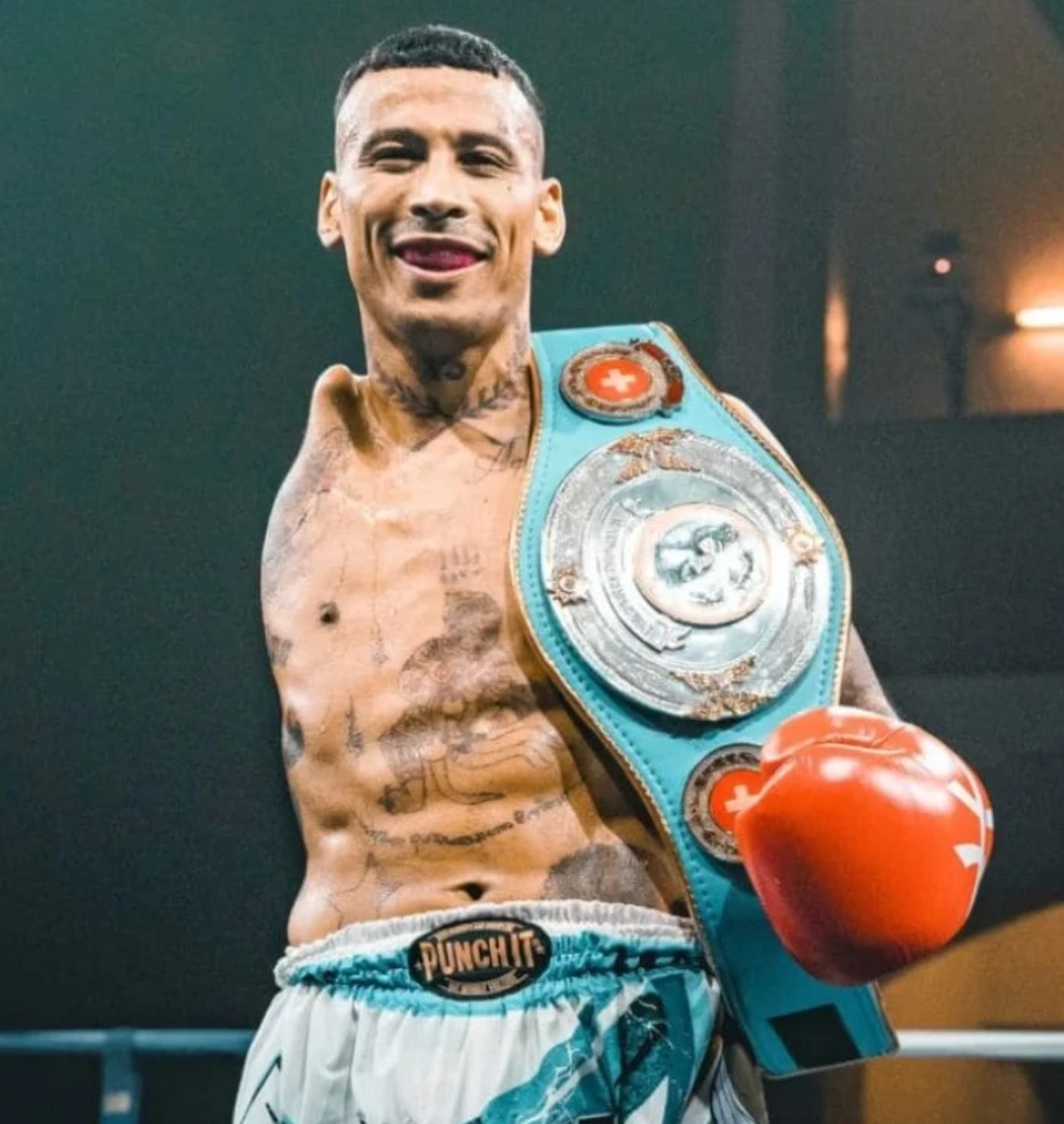 Carlitos Machado smiling with a championship belt over his shoulder
